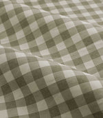 A close-up of draped fabric with a classic gingham check pattern in sage green and off-white.