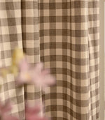 Close-up of Harriet natural beige and cream gingham curtain fabric hanging in soft folds, showing the classic checked pattern and woven texture.
