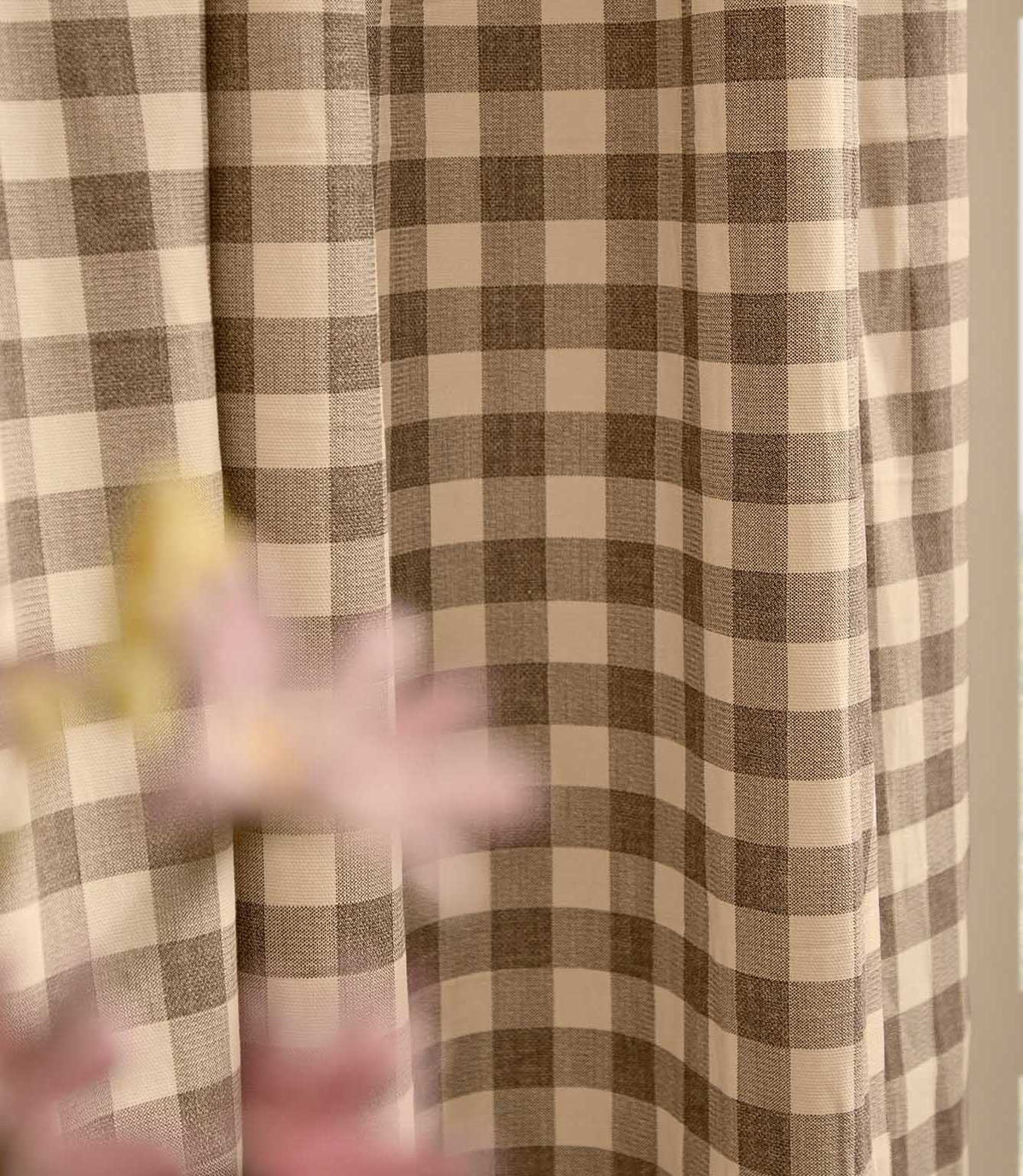 Close-up of Harriet natural beige and cream gingham curtain fabric hanging in soft folds, showing the classic checked pattern and woven texture.