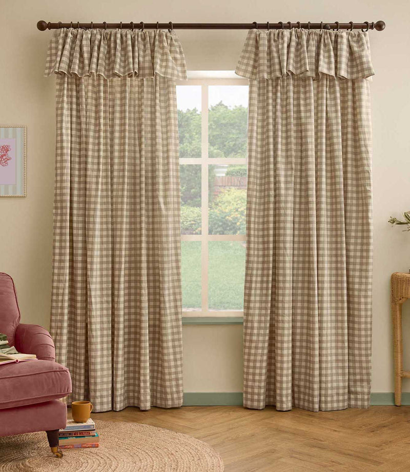 Pair of natural beige and cream gingham check curtains with ruffle flop-top headers framing a large window in a softly styled living room.