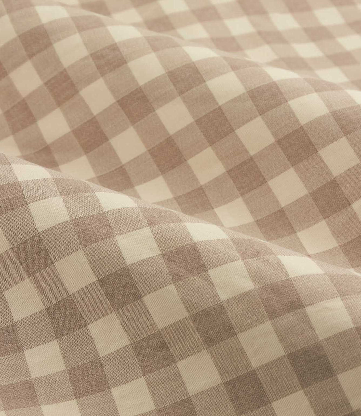Close-up detail of natural beige and cream gingham check cotton curtain fabric arranged in soft folds, showing the woven texture and checked pattern.