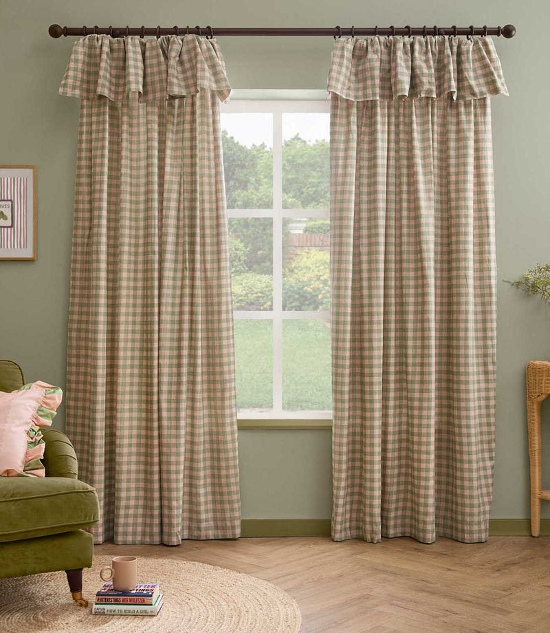 Pair of Harriet pink and sage green gingham check fully lined curtains with ruffle flop-top headers, framing a large window in a relaxed living room.