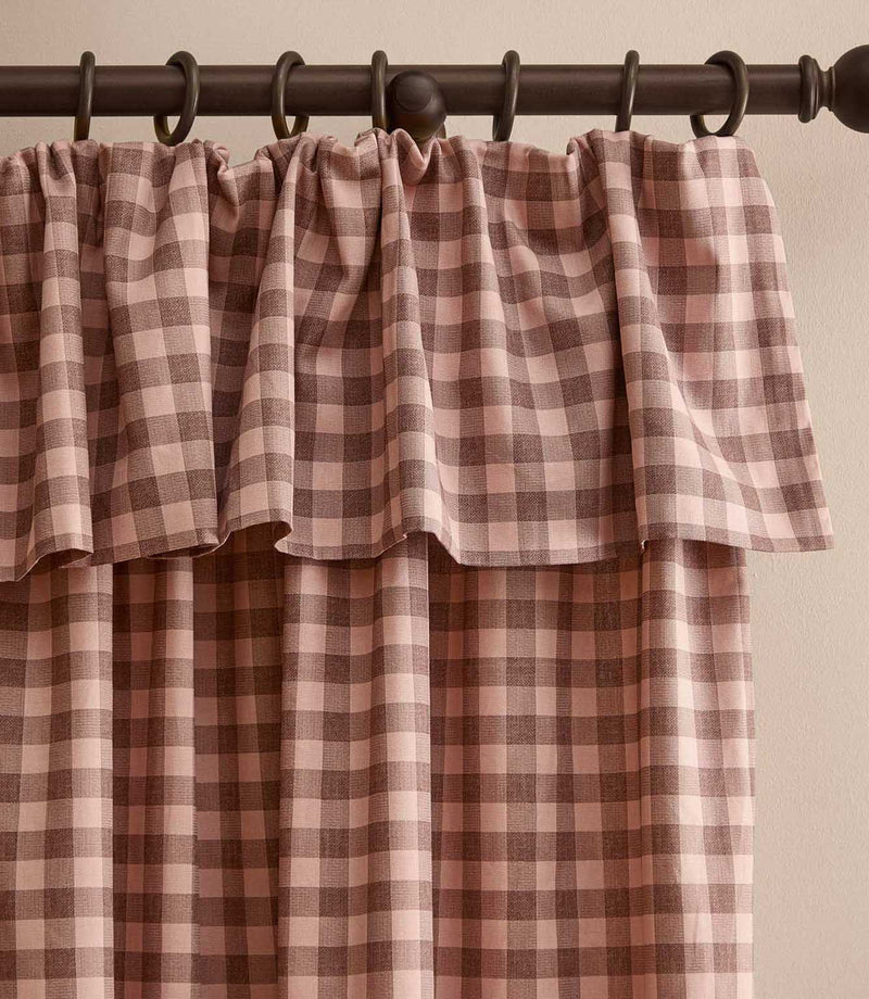 Harriet pink and brown gingham check fully lined curtain with a softly gathered ruffle flop-top header, hanging from a dark wooden curtain pole.