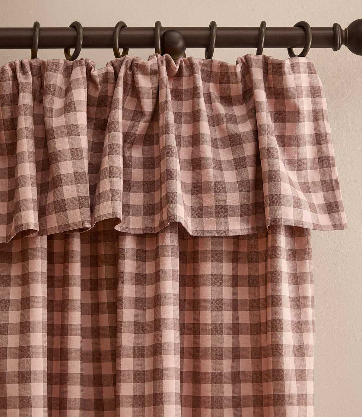 Harriet pink and brown gingham check fully lined curtain with a softly gathered ruffle flop-top header, hanging from a dark wooden curtain pole.
