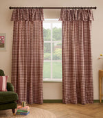 Pair of Harriet pink and brown gingham check fully lined curtains with gathered ruffle flop-top headers, framing a large window in a relaxed living room.
