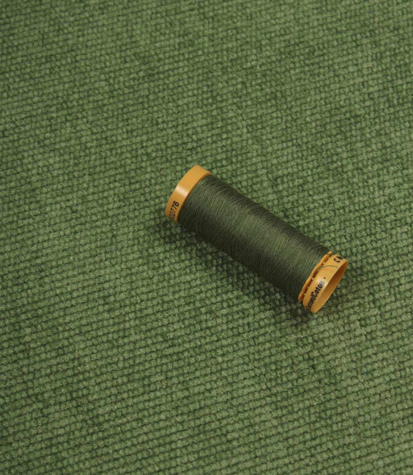 Hartwell emerald green upholstery fire retardant fabric displayed with a coordinating Gutermann thread spool.