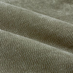 Close-up of eucalyptus green washed velvet curtain fabric arranged in soft folds, highlighting its plush feel, subtle ribbed texture and gently mottled finish.