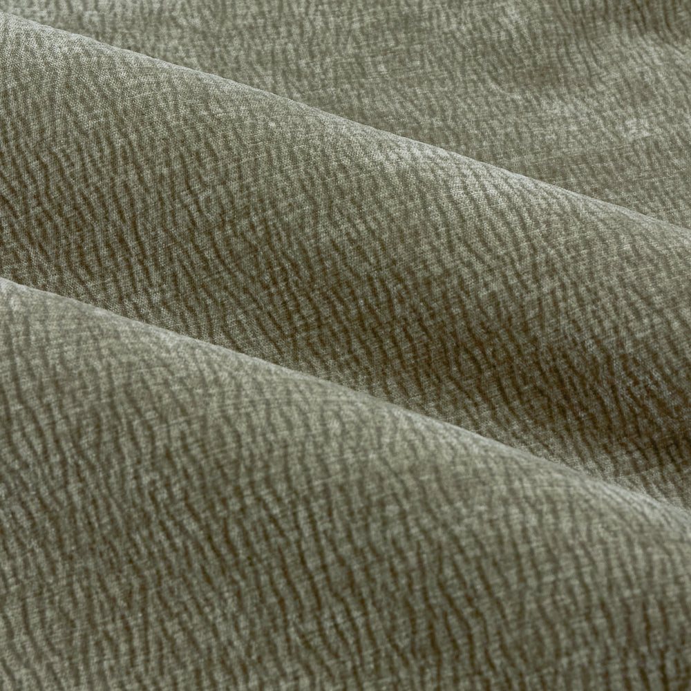 Close-up of eucalyptus green washed velvet curtain fabric arranged in soft folds, highlighting its plush feel, subtle ribbed texture and gently mottled finish.