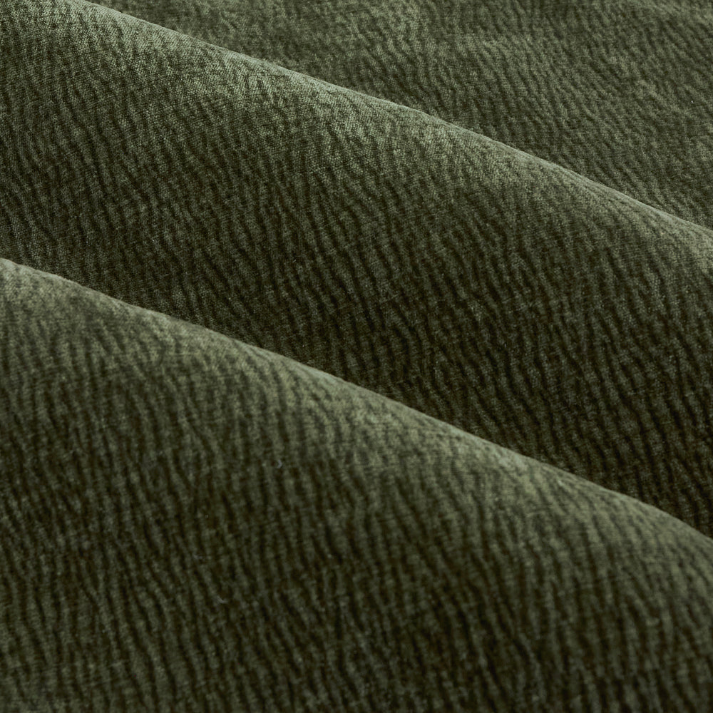 Close-up of olive green washed velvet curtain fabric arranged in soft folds, highlighting its plush surface, fine rippled texture and subtle tonal variation.