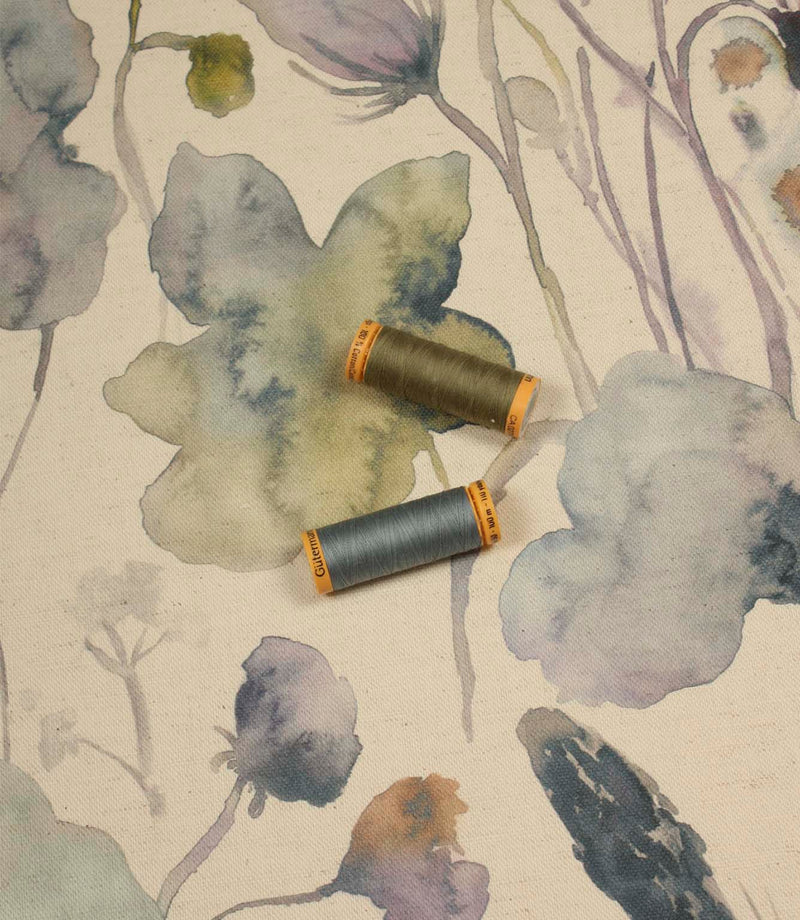 Hibberia Crocus cotton fabric with matching thread spools, highlighting the floral pattern in soft blue, green and lilac tones.