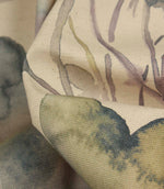 Detailed close-up of Hibberia Crocus cotton fabric showing the textured weave and watercolour floral motifs in soft blue, green and purple tones.