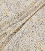 Hitherhill Gull floral fabric arranged in soft, flowing folds, showcasing its layered botanical pattern of stylised leaves, delicate flowers and branching foliage in muted grey, taupe and pale gold tones against an ivory background.