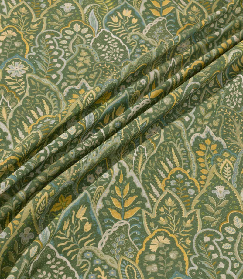 Hitherhill Kelp floral fabric arranged in soft, flowing folds, showcasing its detailed botanical pattern of layered foliage, delicate flowers and decorative leaf motifs in deep forest green, olive, golden yellow, muted blue and cream, with the folds highlighting the fabric's drape and printed detail.