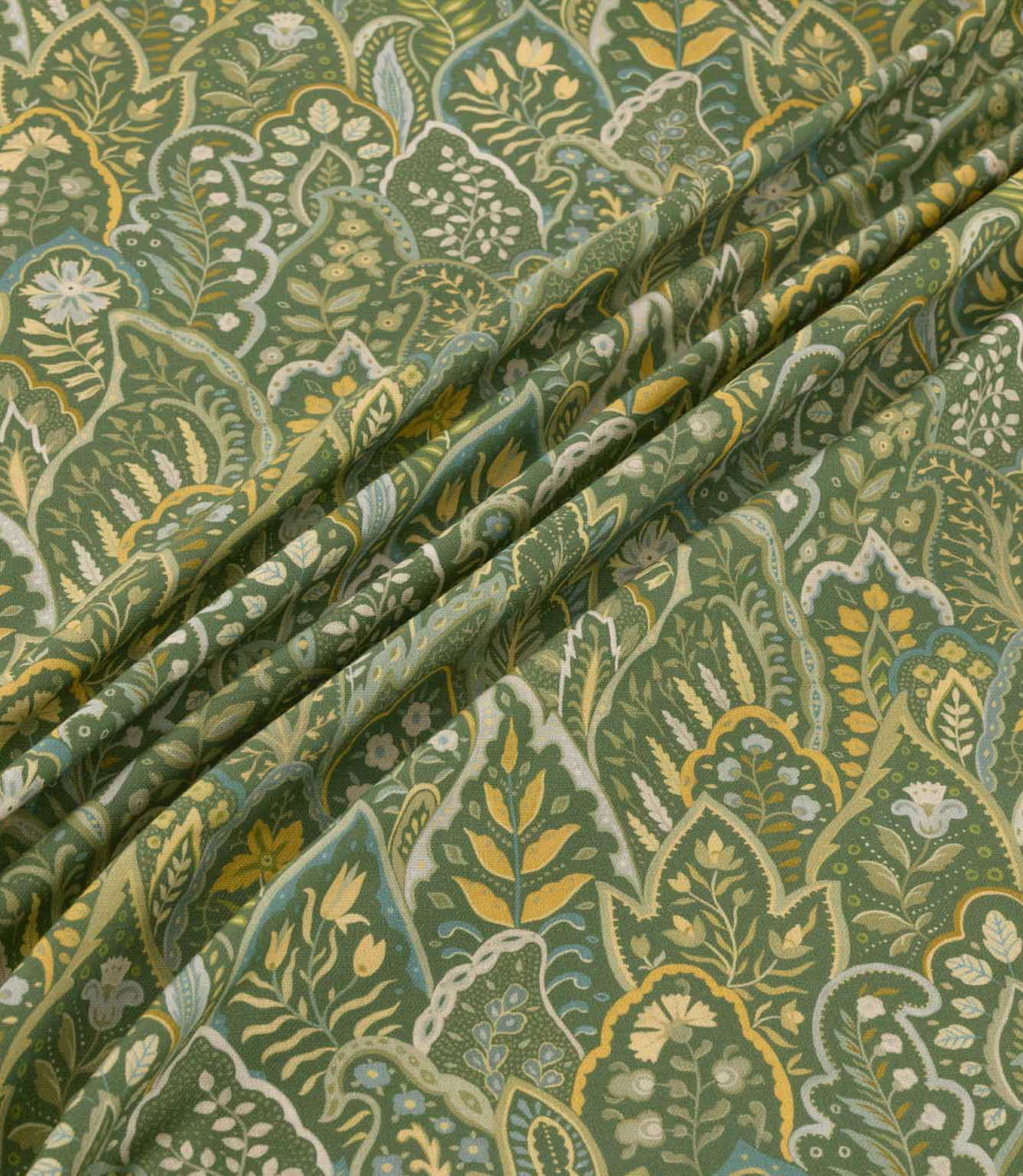 Hitherhill Kelp floral fabric arranged in soft, flowing folds, showcasing its detailed botanical pattern of layered foliage, delicate flowers and decorative leaf motifs in deep forest green, olive, golden yellow, muted blue and cream, with the folds highlighting the fabric's drape and printed detail.