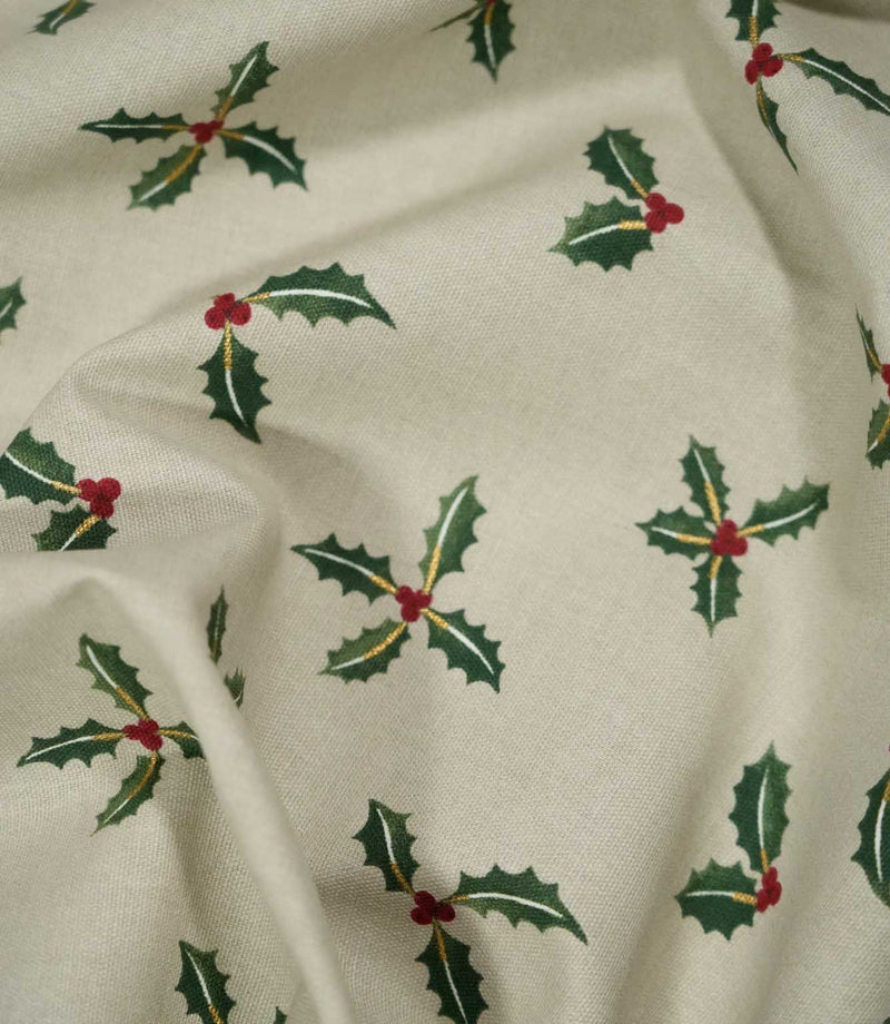 Draped Holly and Berry Stone Christmas fabric displaying its woven texture and scattered festive pattern of green holly leaves, red berries and gold detailing.