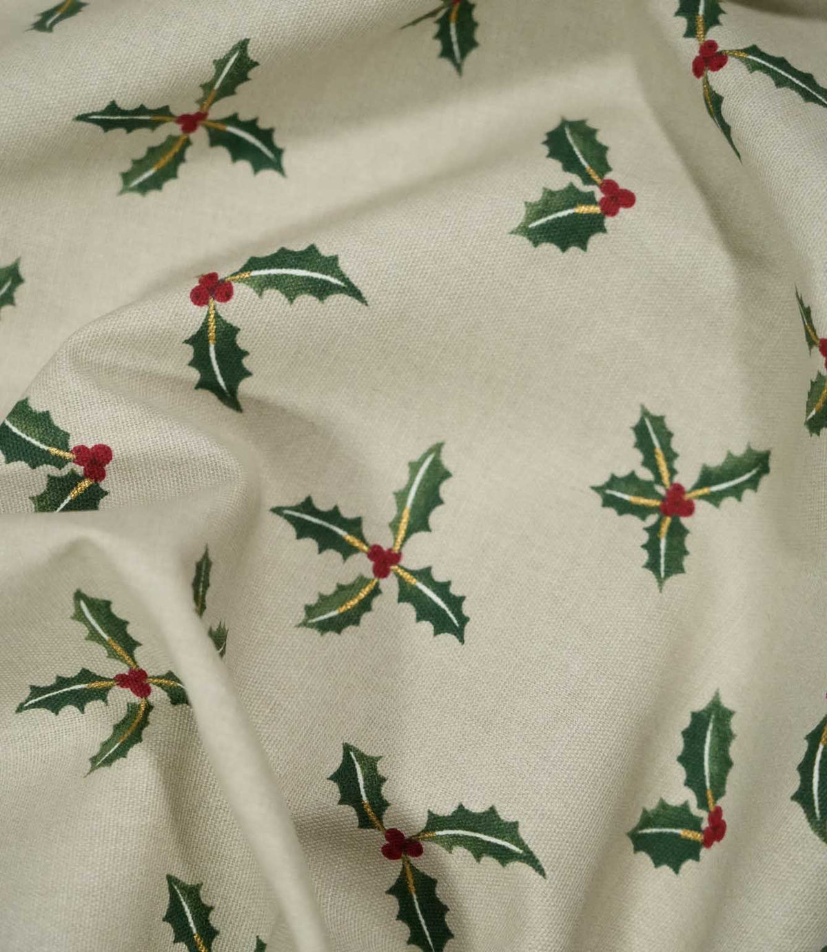 Draped Holly and Berry Stone Christmas fabric displaying its woven texture and scattered festive pattern of green holly leaves, red berries and gold detailing.