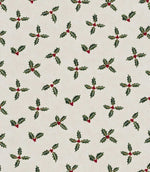 Festive fabric with repeating pattern of green holly leaves with small red berries on a warm off-white background.