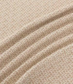 Horton Quaker taupe and cream geometric fabric arranged in flowing folds, showing its small-scale pattern and textured surface.