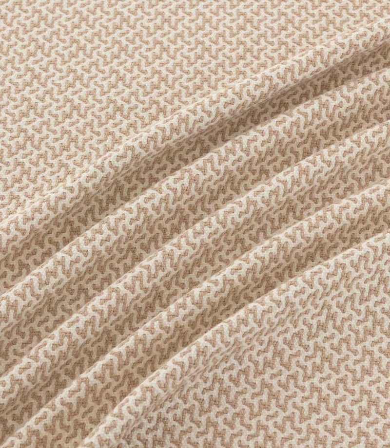 Horton Quaker taupe and cream geometric fabric arranged in flowing folds, showing its small-scale pattern and textured surface.