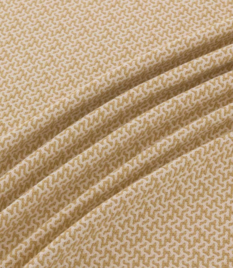 Horton Sandytan golden sand and cream geometric fabric arranged in diagonal folds, showing its textured weave and repeating pattern.