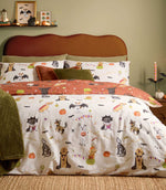 Howl-O-Ween multicolour reversible duvet cover set with illustrated dogs in Halloween costumes, orange pumpkins and black bats on a cream background, styled with rust and olive green cushions.