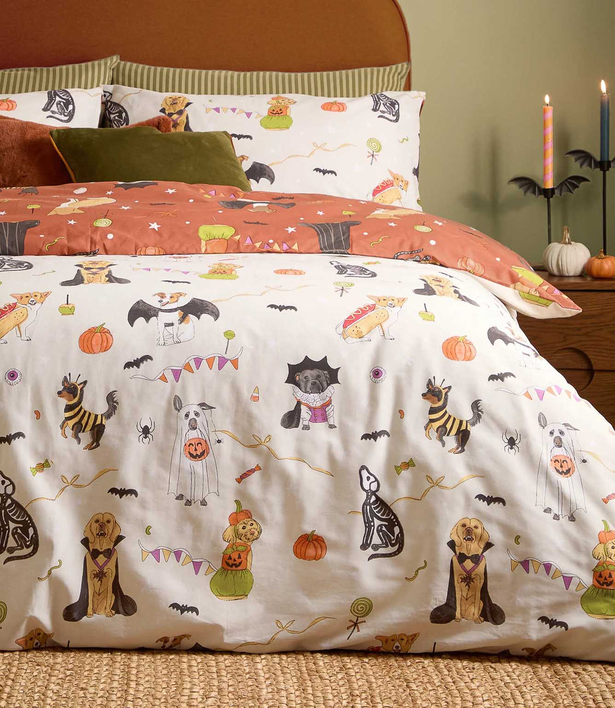 Howl-O-Ween reversible Halloween duvet cover displayed on the cream side, featuring multicoloured costumed dogs, orange pumpkins, black bats and playful party motifs.
