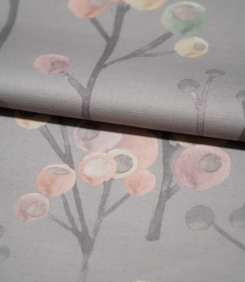Ichiyo contemporary botanical fabric folded over itself, showing its smooth woven texture and repeating pink, cream and pale green floral design on grey.