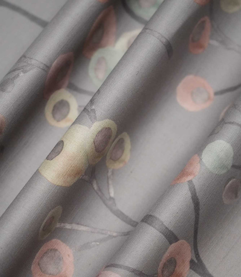 Ichiyo fabric arranged in soft folds, displaying its flowing grey branches and scattered pastel pink, cream and mint green circular floral motifs.