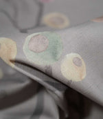 Detailed close-up of Ichiyo fabric showing the fine woven texture, soft grey background and delicate mint green and pale yellow circular botanical motifs.