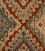 Close-up of a patterned geometric fabric with red, beige, and brown colours.