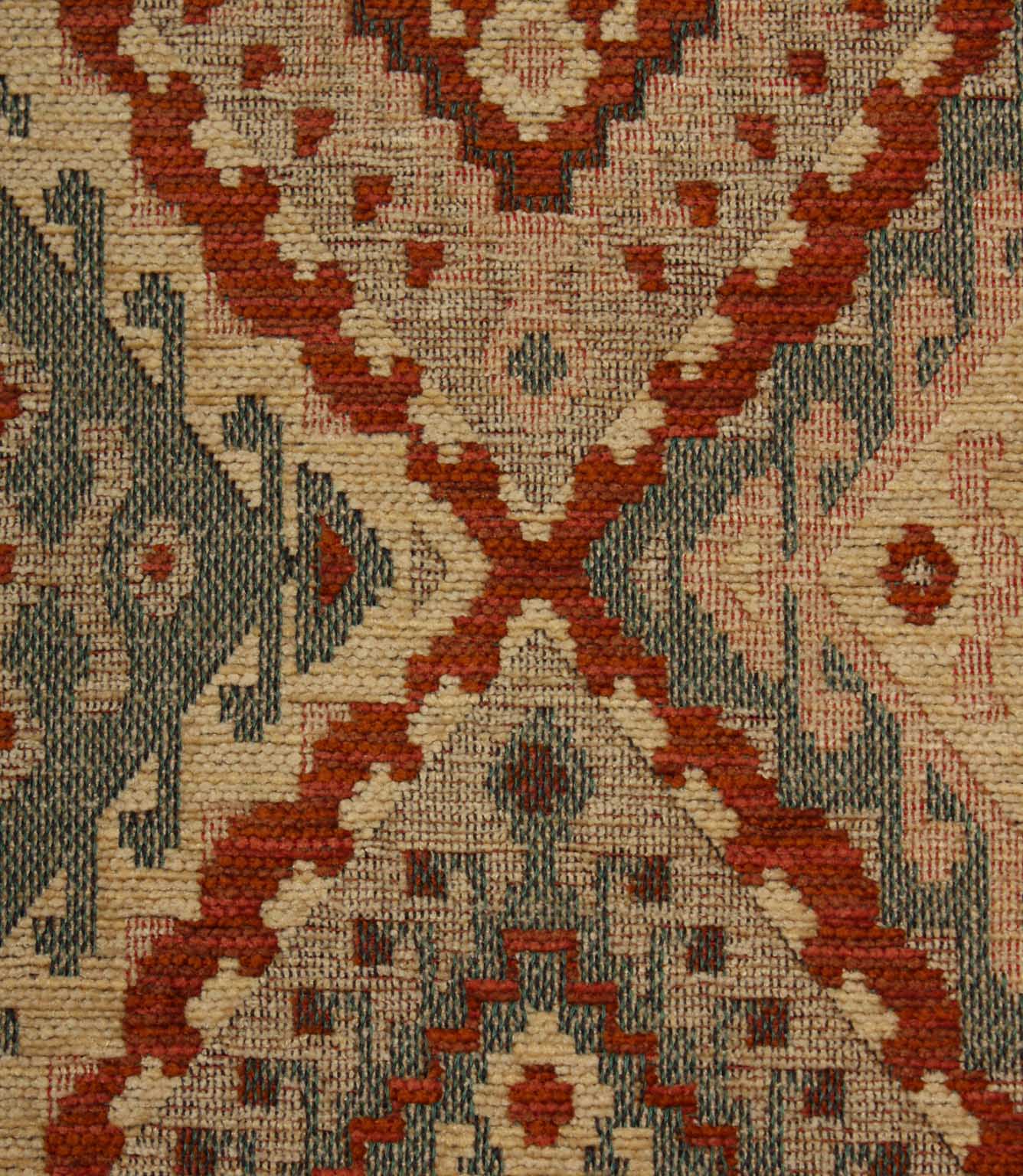 Close-up of a patterned geometric fabric with red, beige, and brown colours.