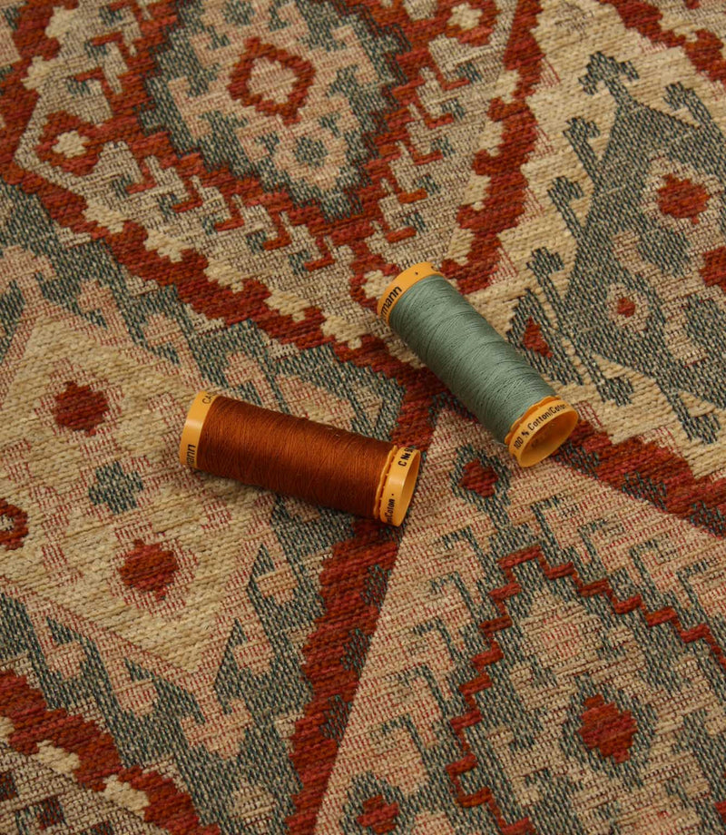 Two spools of thread on a patterned geometric fabric background