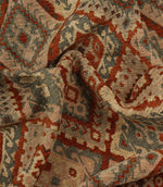 Close-up of patterned geometric fabric with red, beige, and brown colours.