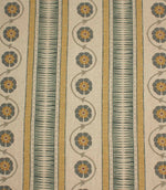 Decorative stripe fabric in muted mustard, slate blue, and taupe with repeating floral vine motifs on a natural background.