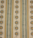 Decorative stripe fabric in muted mustard, slate blue, and taupe with repeating floral vine motifs on a natural background.