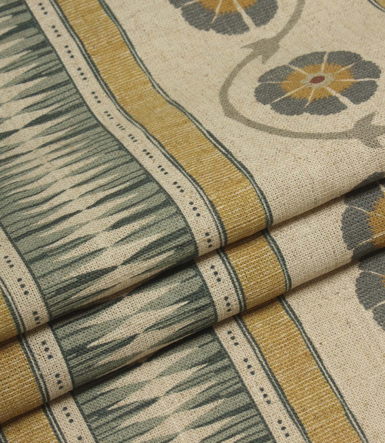 Folded striped fabric featuring decorative geometric panels and repeating floral motifs in muted heritage-inspired colours.