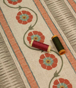 Floral stripe fabric shown with coordinating thread spools in rich red and deep olive green for colour matching inspiration.