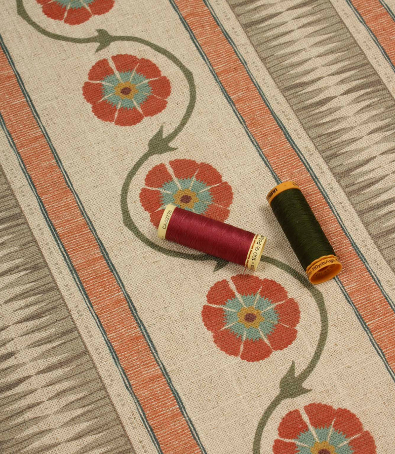 Floral stripe fabric shown with coordinating thread spools in rich red and deep olive green for colour matching inspiration.