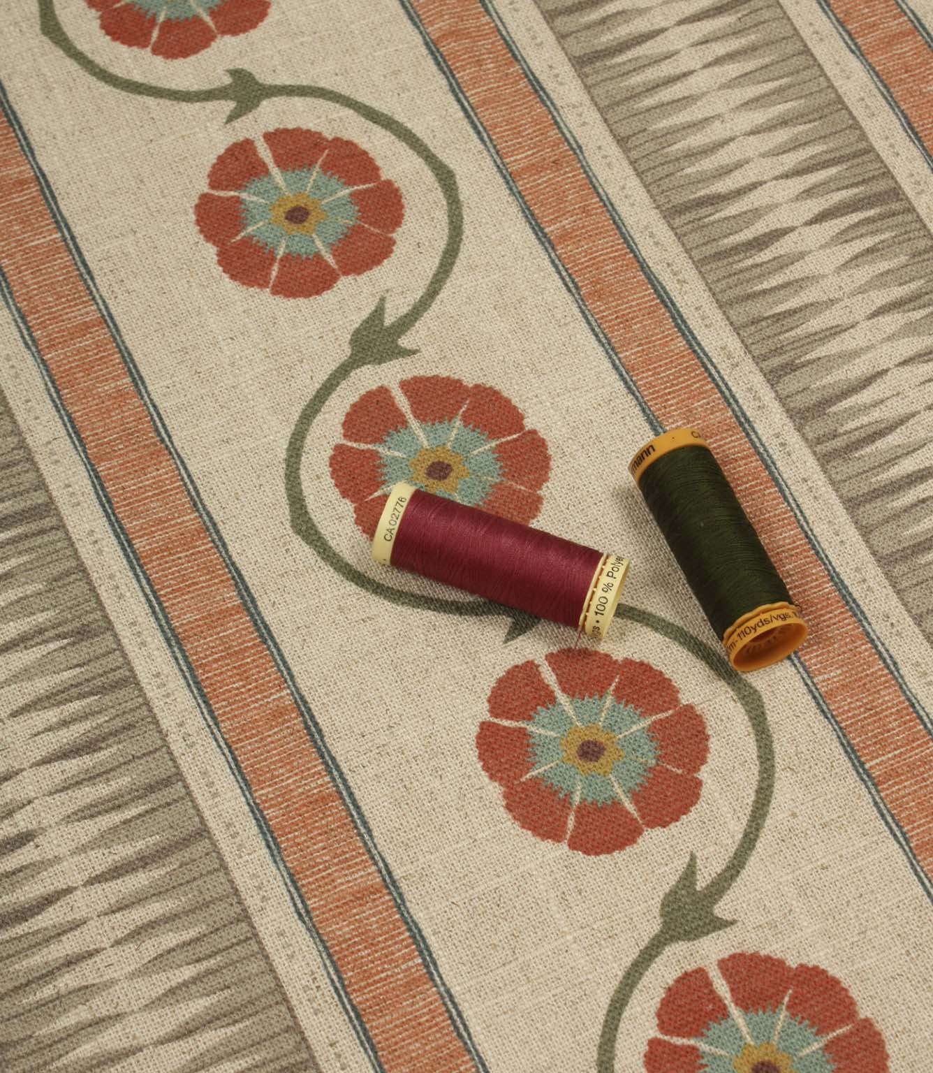 Floral stripe fabric shown with coordinating thread spools in rich red and deep olive green for colour matching inspiration.