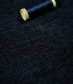 Insernia Velvet Night fabric laid flat with a coordinating dark navy thread spool, highlighting the rich blue-black shade, fine textured appearance and soft velvet finish.
