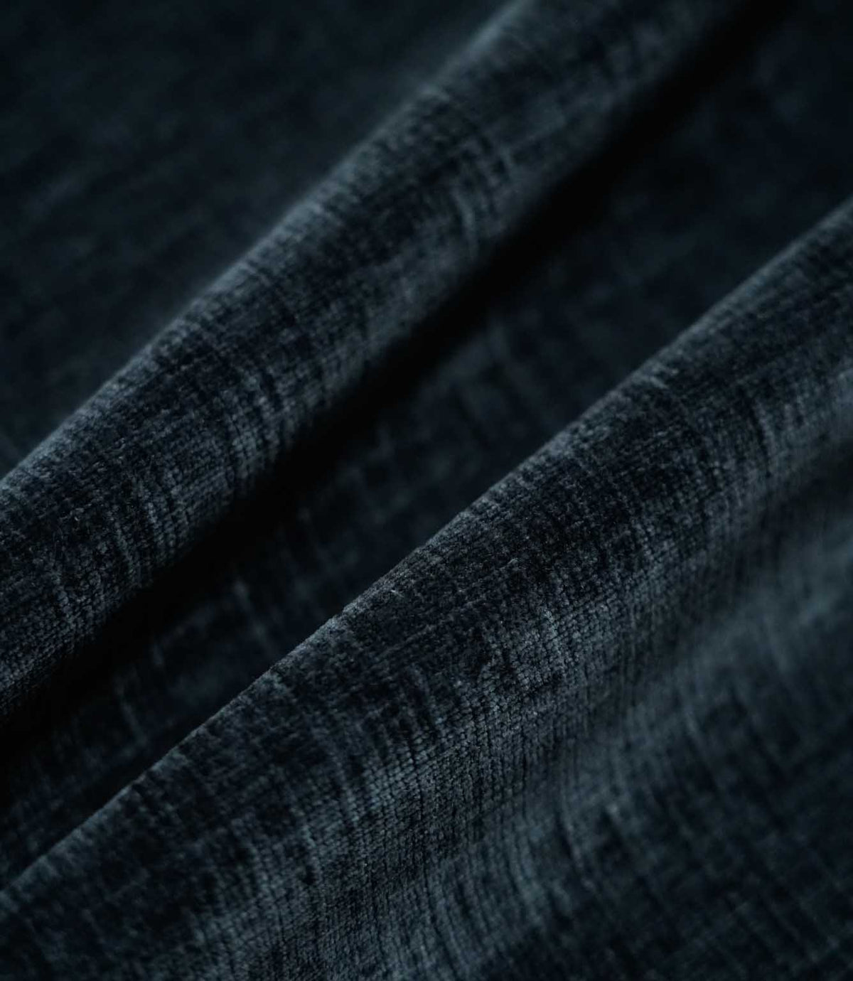 Insernia Velvet Night fabric arranged in flowing folds, showcasing its deep charcoal navy colour, gently mottled velvet texture and subtle sheen as the light catches the surface.