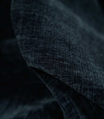 Macro photograph of Insernia Velvet Night fabric draped in soft folds, revealing the plush velvet pile, fine crosshatched texture and subtle tonal variations in dark navy and charcoal.
