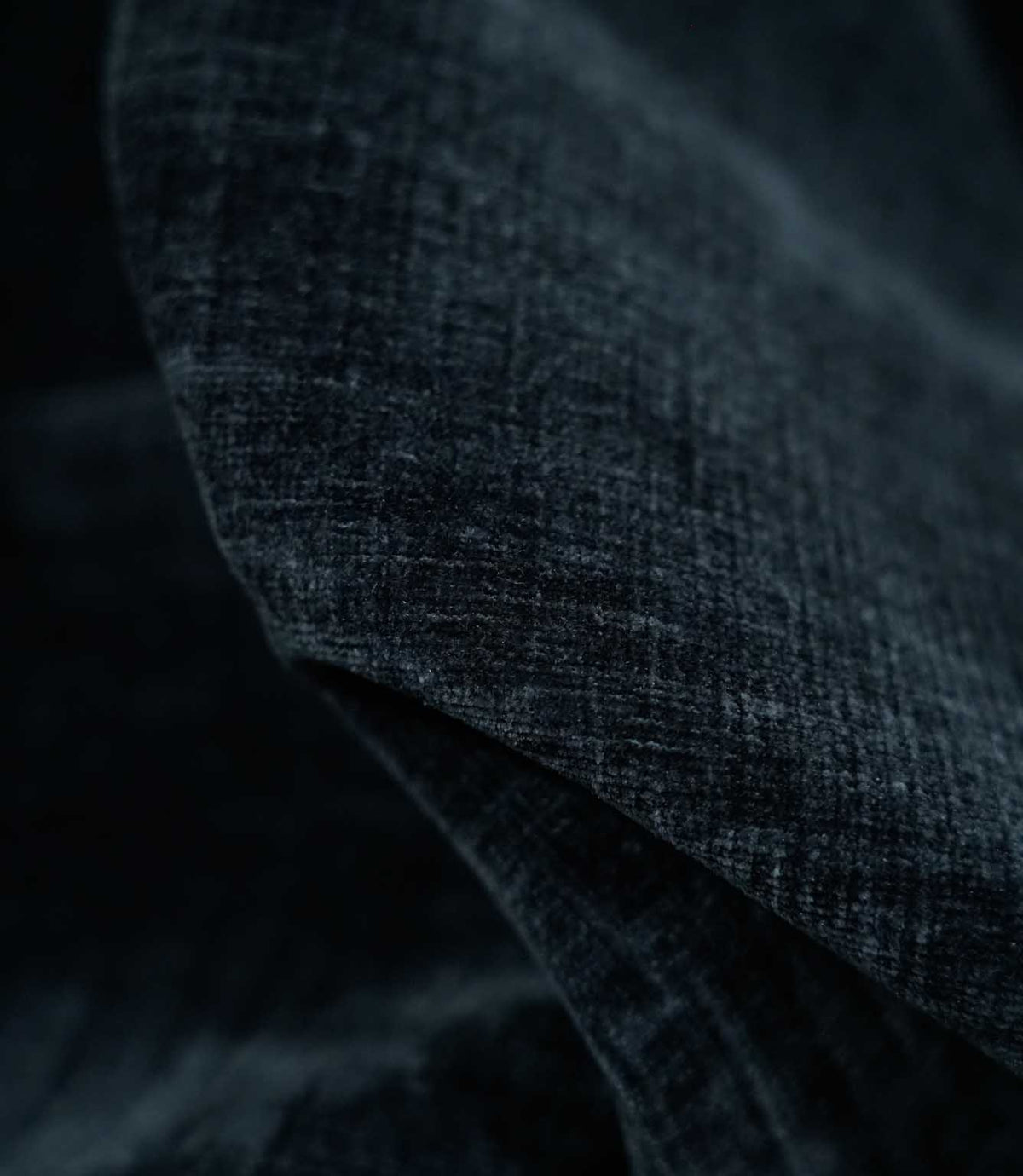 Macro photograph of Insernia Velvet Night fabric draped in soft folds, revealing the plush velvet pile, fine crosshatched texture and subtle tonal variations in dark navy and charcoal.