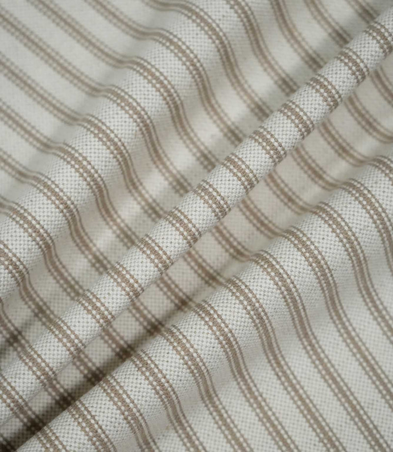 Beige ticking stripe fabric draped into soft folds, showing the natural woven texture and evenly spaced taupe-beige striped pattern.