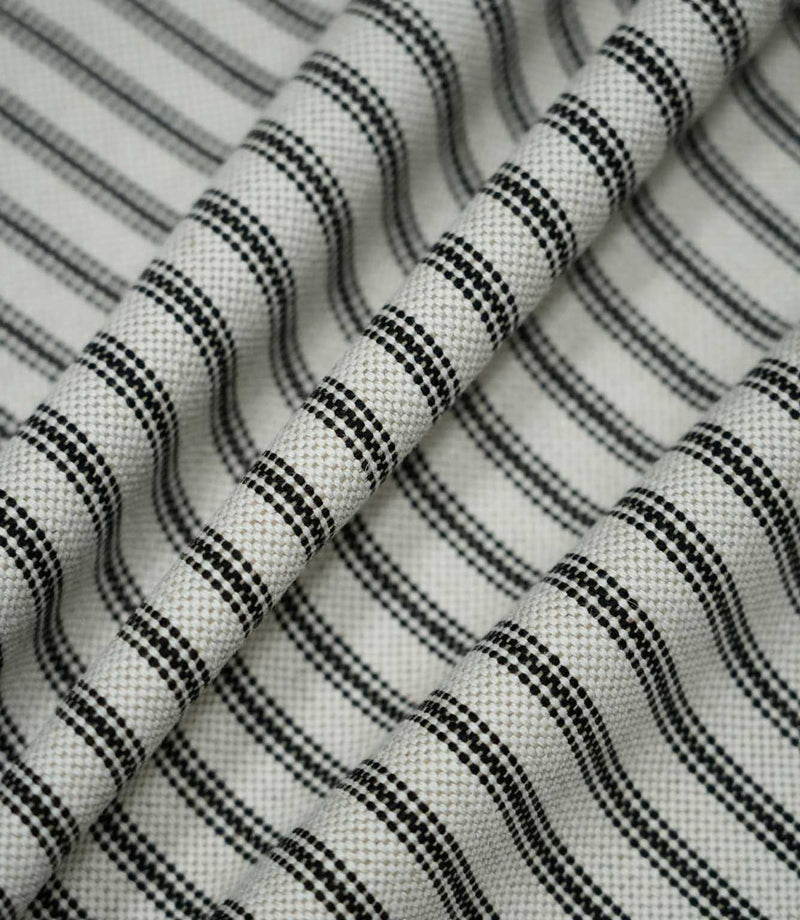 Black ticking stripe fabric arranged in soft folds, showing how the classic black and cream striped pattern drapes while retaining its textured woven finish.