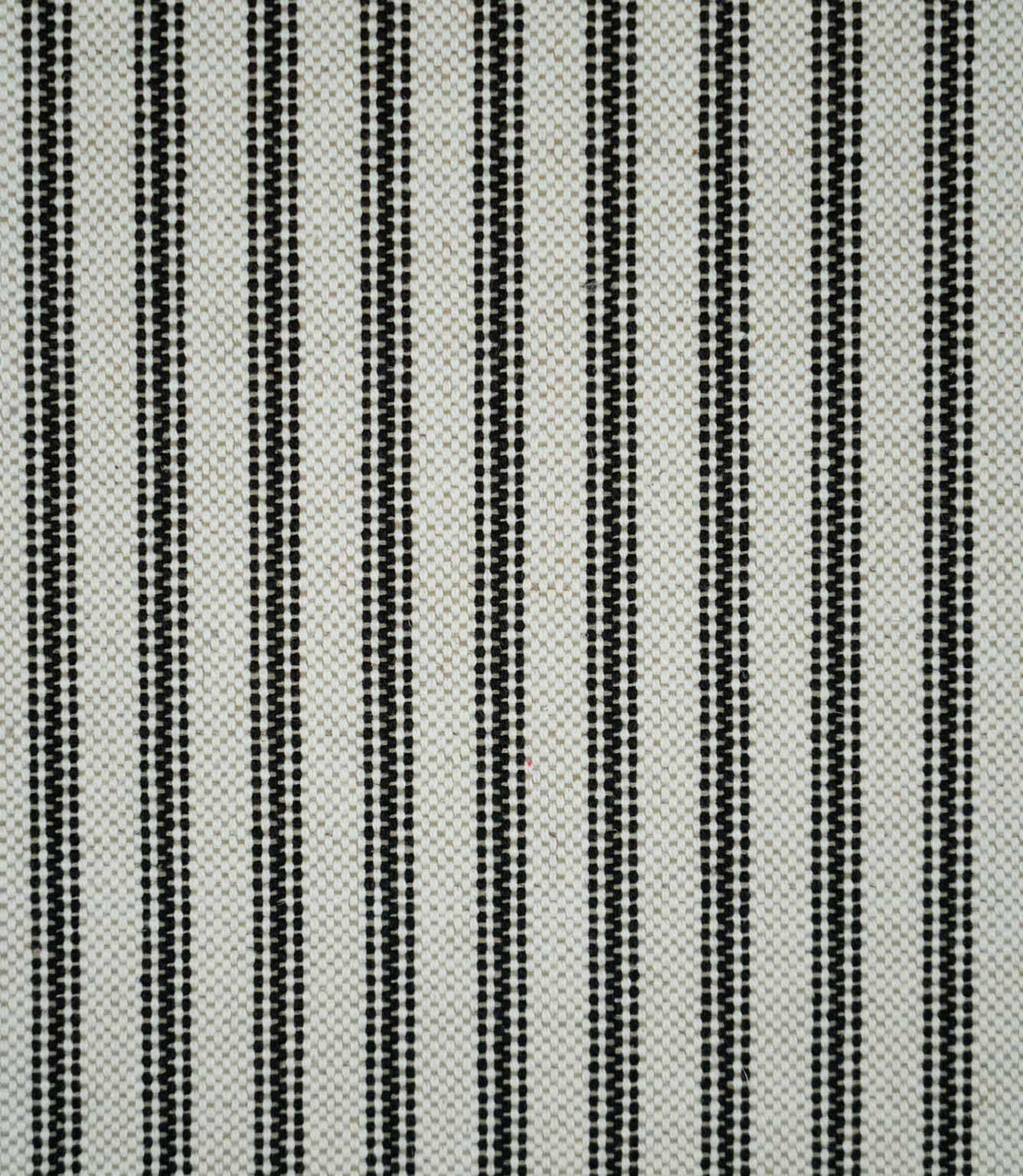 Full view of black ticking stripe fabric featuring evenly spaced narrow black woven stripes on a natural cream background.