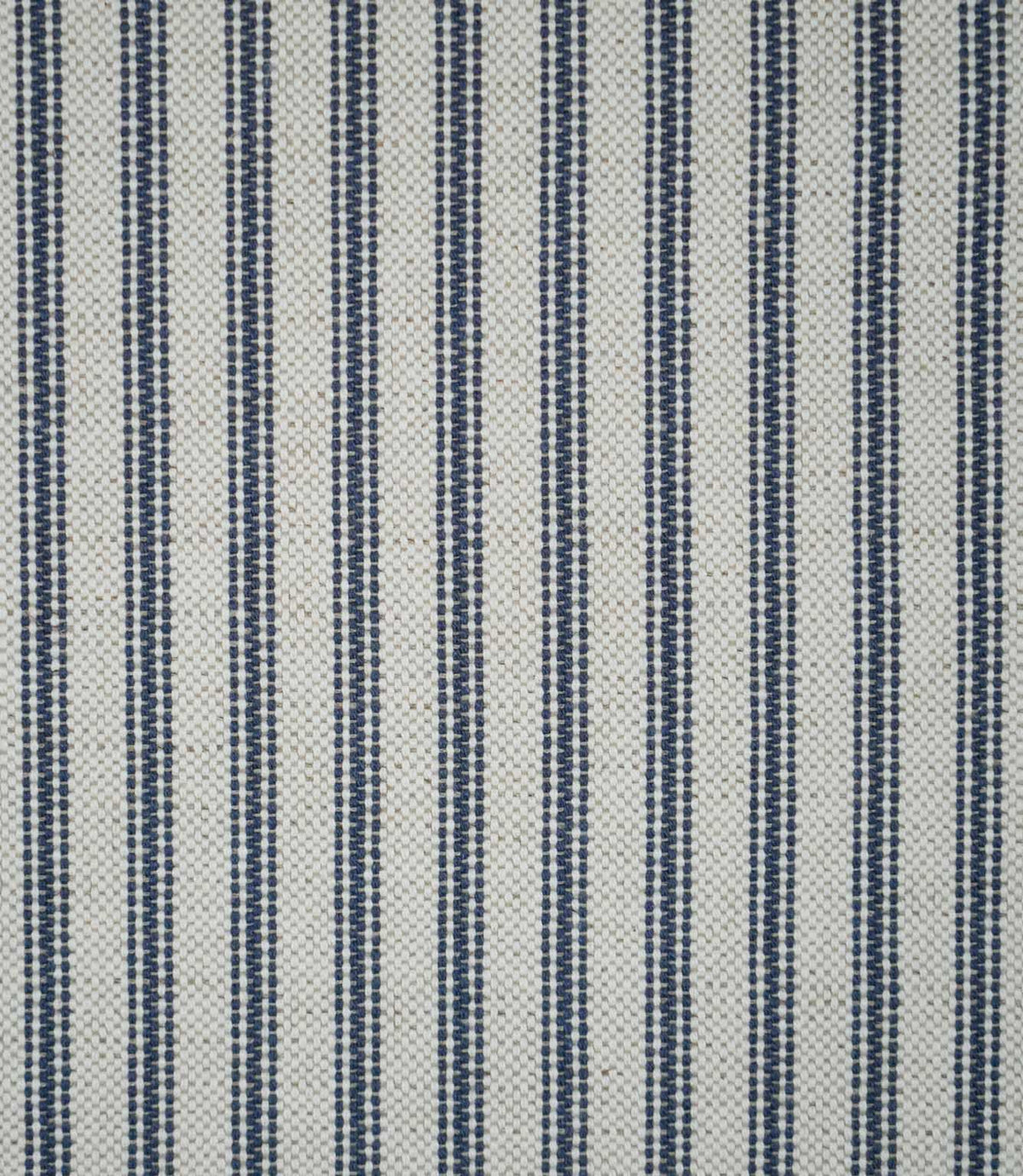Blue ticking stripe fabric with evenly spaced navy blue woven stripes on a natural cream background, showing the classic striped design and textured weave.