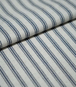 Folded blue ticking stripe fabric showing the repeating navy blue stripe pattern and tactile natural cream woven texture.
