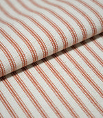 Folded Linen Ticking Burnt Orange fabric displaying its regular woven stripe pattern, natural cream background and textured finish.
