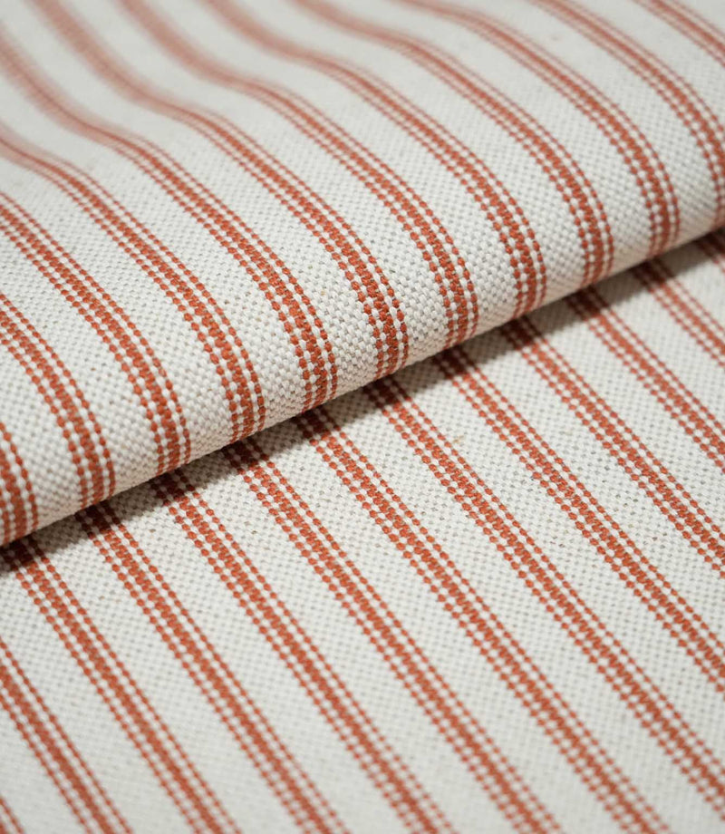 Folded Linen Ticking Burnt Orange fabric displaying its regular woven stripe pattern, natural cream background and textured finish.
